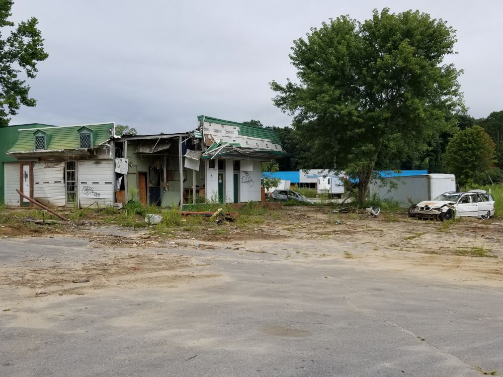 A destroyed building with an annihilated white car next to it