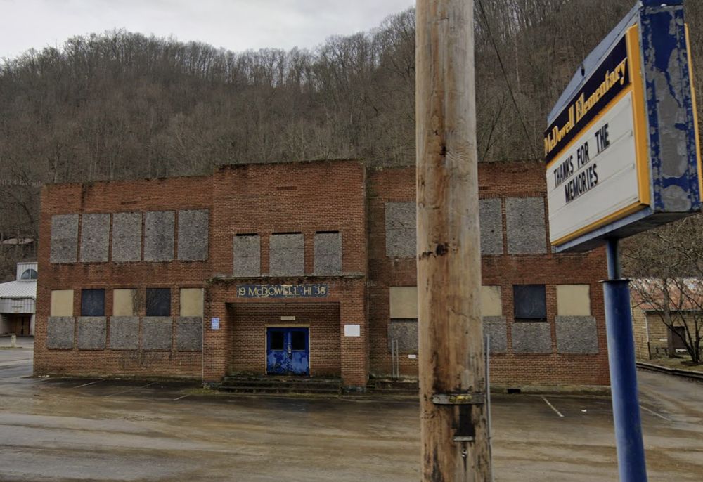 two story brick elementary school, shut and boarded. sign post says "thanks for the memories"