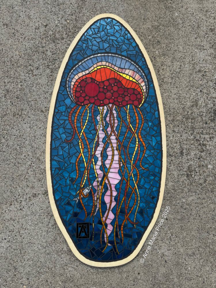 Stained glass mosaic of a jellyfish with fish caught in a tentacle on an upcycled wood skim board.