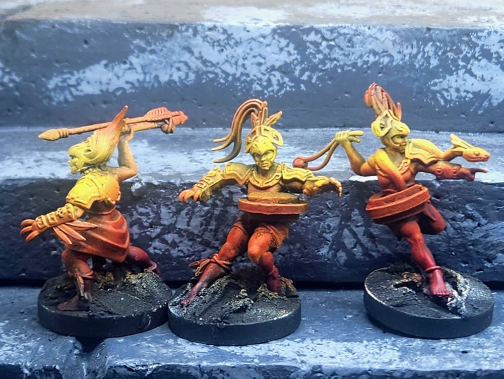 Three airbrushed miniatures representing mesoamerican woman warriors and ballplayers, painted a smooth red to orange to yellow gradient.