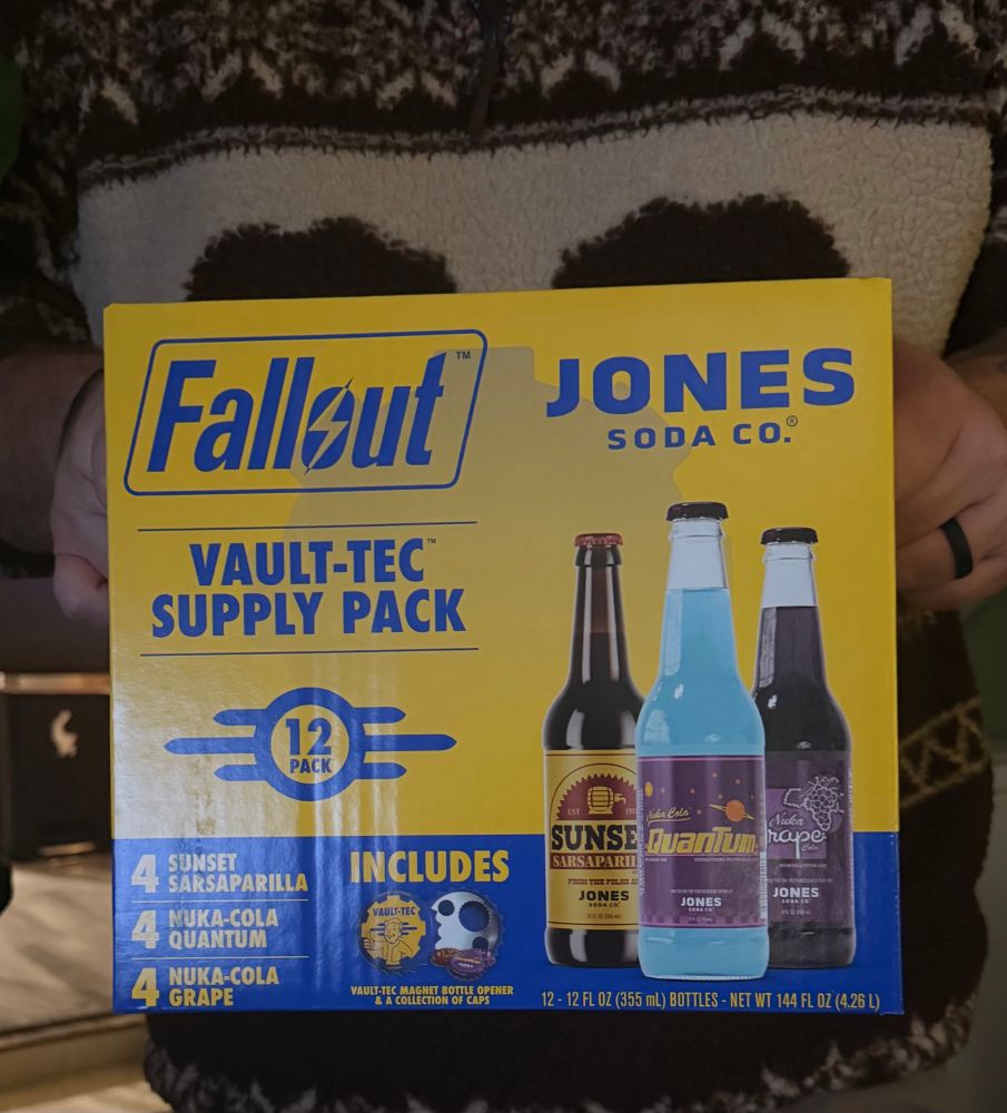 A holding the Fallout pack of Jones Soda Co. brand soda. 4 sunset sarsaparilla 4 nuka-cola quantum 4 nuka cola grape 