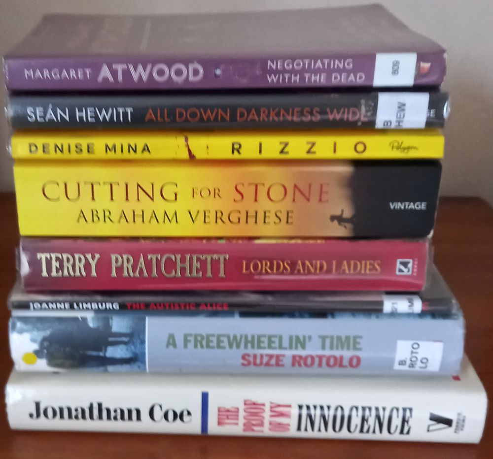 A pile of library books: The Proof of my Innocence by Jonathan Coe, A Freewheelin’ Time by Suze Rotolo, The Autistic Alice by Joanne Limburg, Lords and Ladies by Terry Pratchett, Cutting for Stone by Abraham Verghese, Rizzio by Denise Mina, All Down Darkness Wide by Sean Hewitt, Negotiating with the Dead by Margaret Atwood.