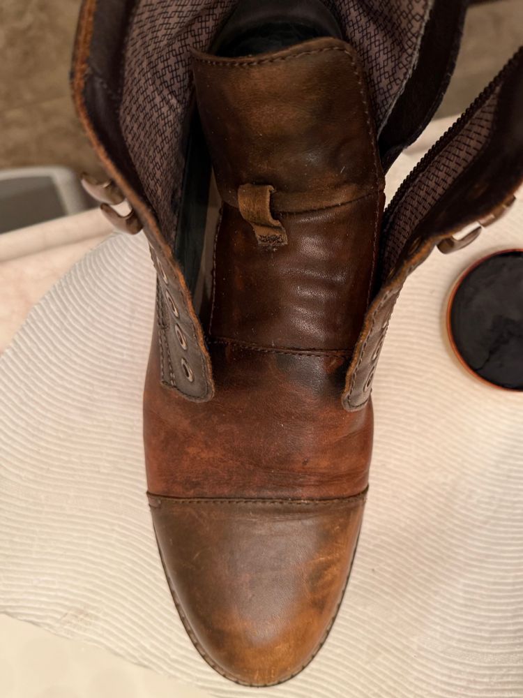 Photo of one unpolished brown boot without laces and an open can of brown Kiwi shoe polish. 