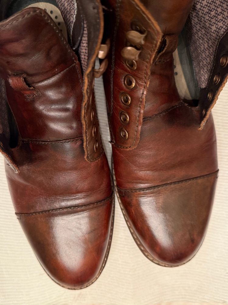 Photo of two polished and buffed brown boots without laces. 