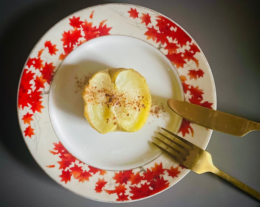 紅葉の絵柄の皿に半分に切った焼きリンゴが乗っている写真です。
リンゴの断面にはシナモンパウダーがかかっています。