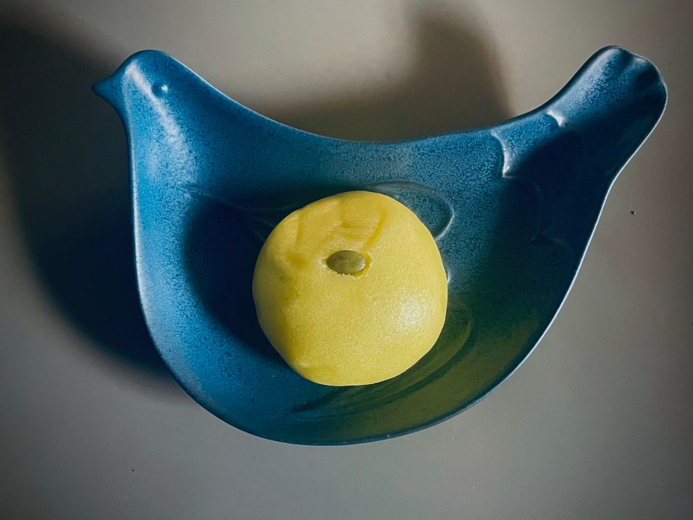 かぼちゃ饅頭の写真です。
丸く黄色い饅頭の天辺にはかぼちゃの種がひと粒乗っています。