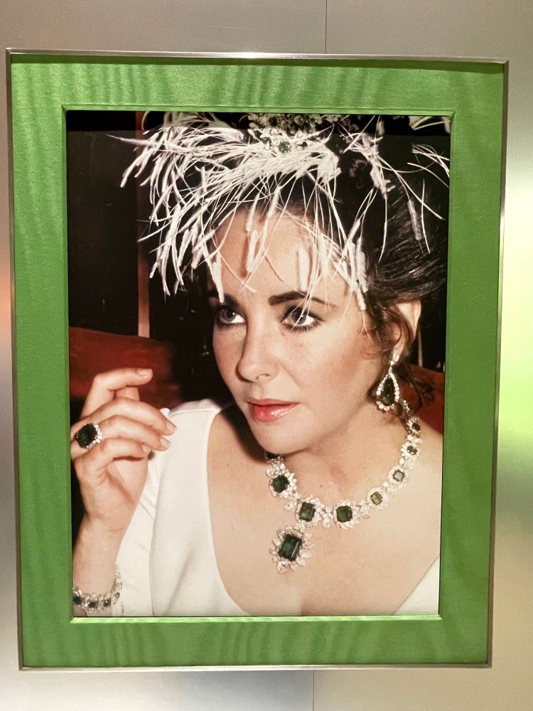 俳優のエリザベス・テイラーのポートレイト写真です。ブルガリの大粒のエメラルドを使ったネックレス、リング、ブレスレット、イヤリングを身に纏っています。