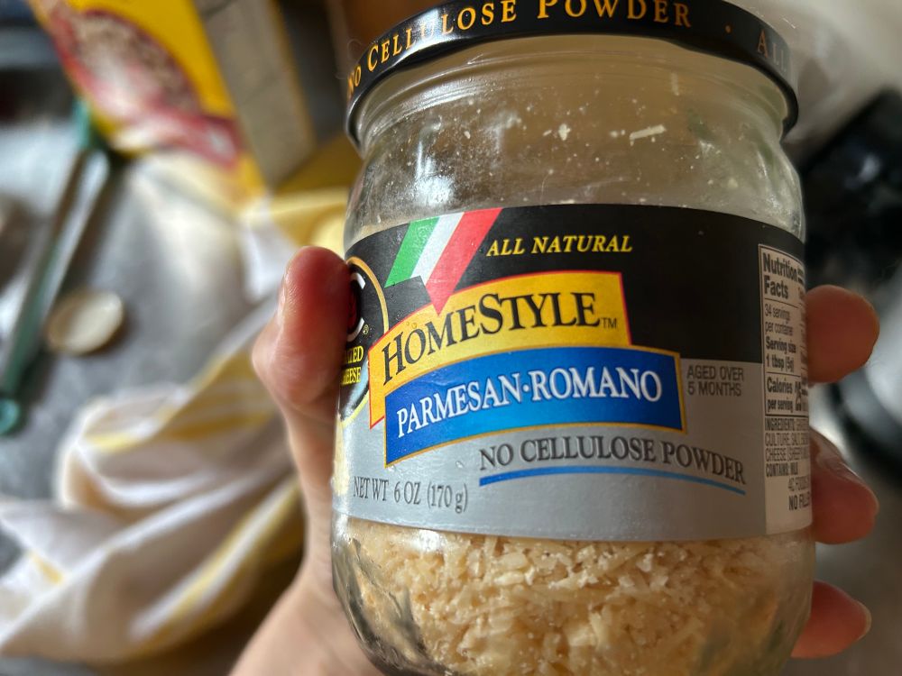 A jar of shredded “Homestyle Parmesan Romano” with “No Cellulose Powder”