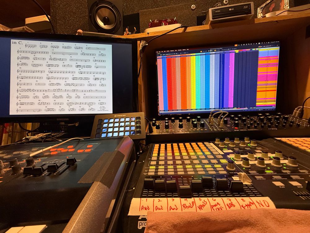 My computer workstation with various controllers, knobs buttons synthesizer, as well as two big monitors. On the left, we have the musical score for “in C”, on the right is the Ableton Live file in which I played the part of 16 performers, each part is color-coded as a column, with 53 measures being represented. It’s quite colorful, and it’s pride month, so why not?