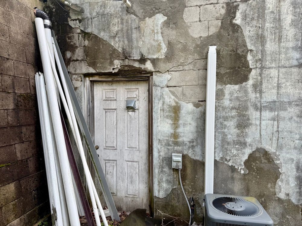 Looking at that door slightly farther away, so you can see the full picture of the poor state of the concrete steps above it and the wall