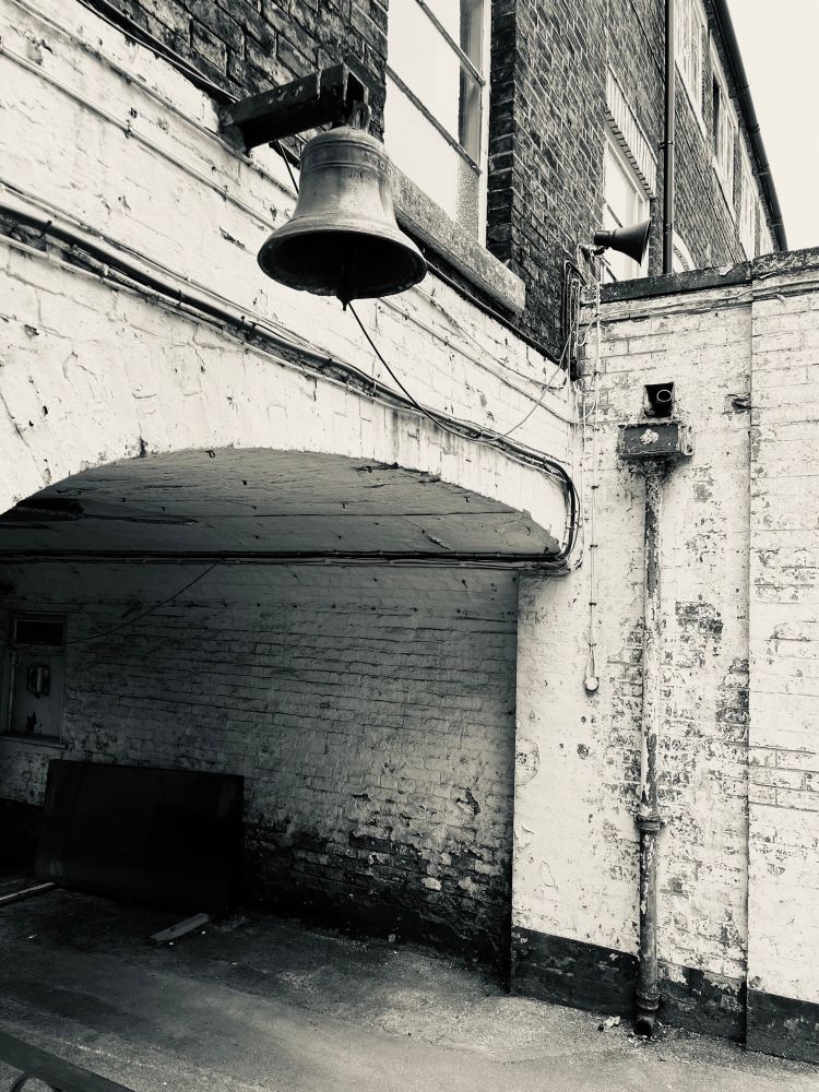 Bell over gateway in the old Spode works in Stoke on Trent. Black and white photo.