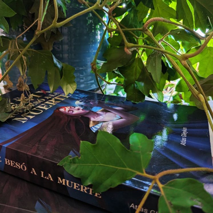 Imagen con el tomo de El fénix que besó a la muerte rodeado de hojas