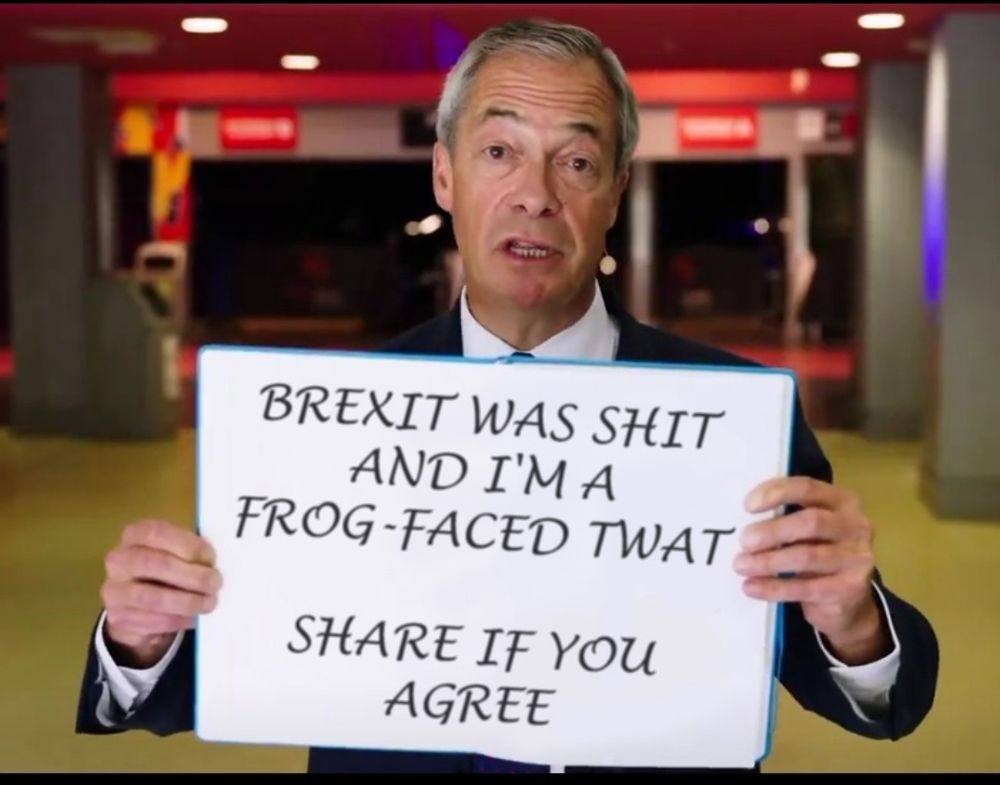 Nigel Farage holding a sign that says 'Brexit was shit and I'm a frog-faced twat. Share if you agree'