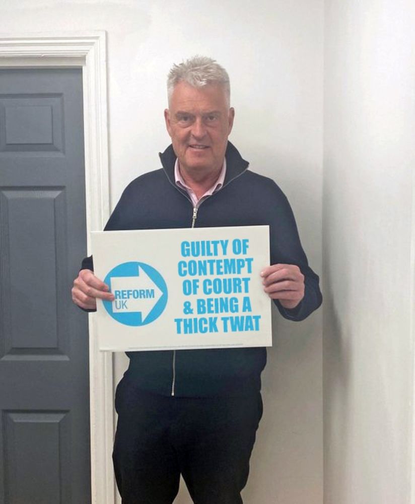 Lee Anderson holding a sign that says 'Guilty of contempt of court and being a thick twat'