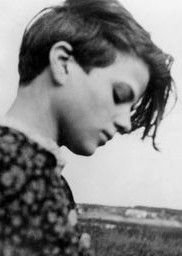 A black and white photo of Sophie Scholl, seen in profile outdoors with a pensive expression, her brown hair falling over her face.