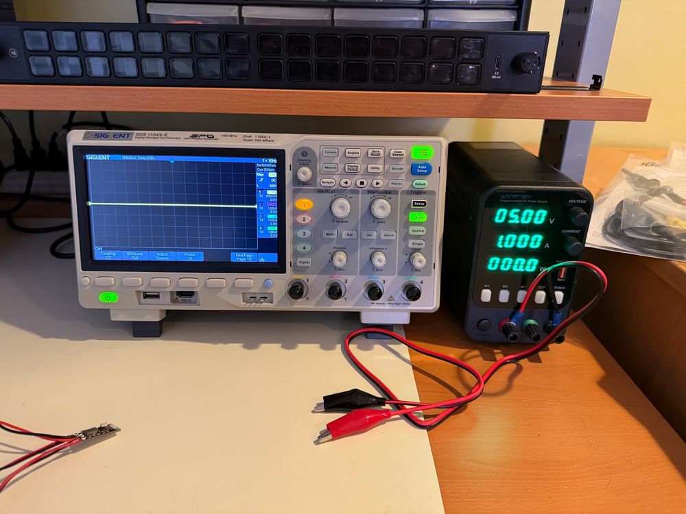 An oscilloscope and a lab power supply turned on and ready to go.  A Stream Deck Studio is just chilling on the shelf above.