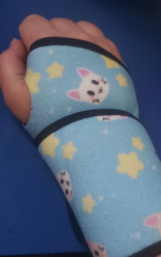Right wrist in blue wrist brace that has cats and stars on it