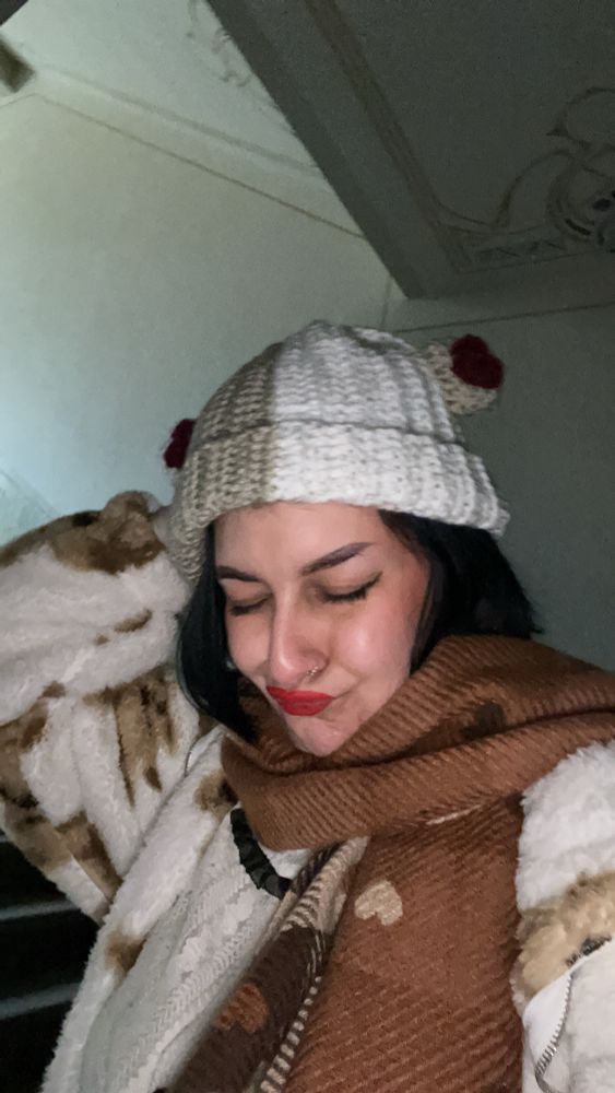 beanie aus strick mit ohren dran und herz patterns an den ohren
der bearnie ist creme farben brain und ich trage eine teddy jacke und einen braunen schal mit herzen drauf 