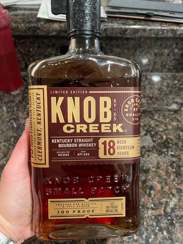 A bottle of Knob Creek 18 year bourbon. It’s a square bottle with a gold and brown label. 