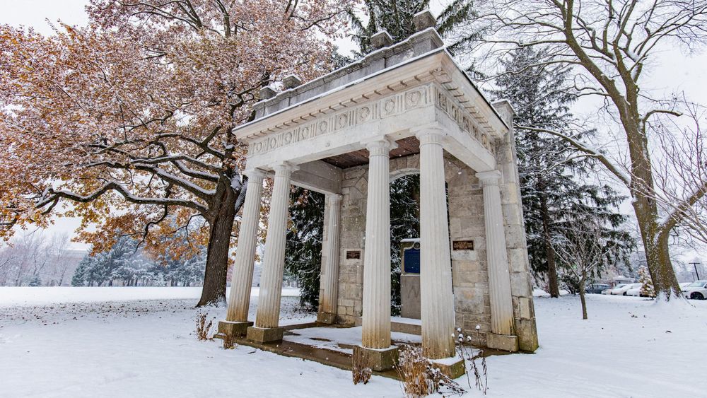 Snow-covered landscape at the University of Guelph on a winter day, with trees partially bare and dusted with snow.
