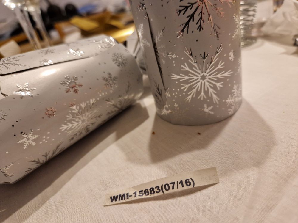 Two Christmas crackers on a tabletop, and a strip of paper bearing only a printed code
