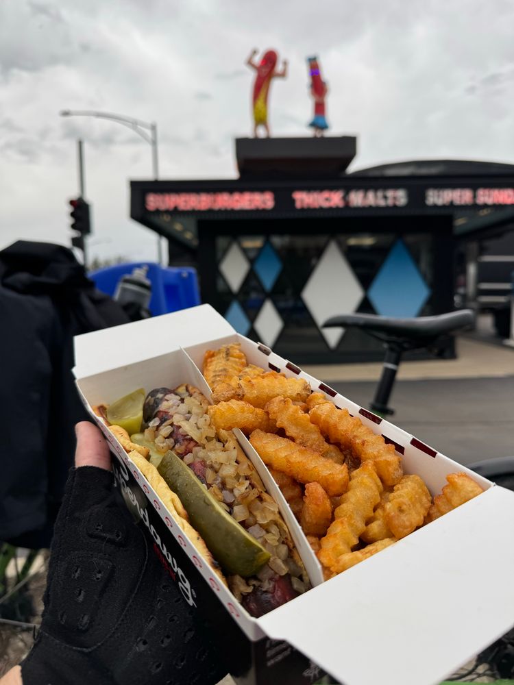 A whoopskidawg from superdawg in front of my bike with the superdawg restaurant in the background