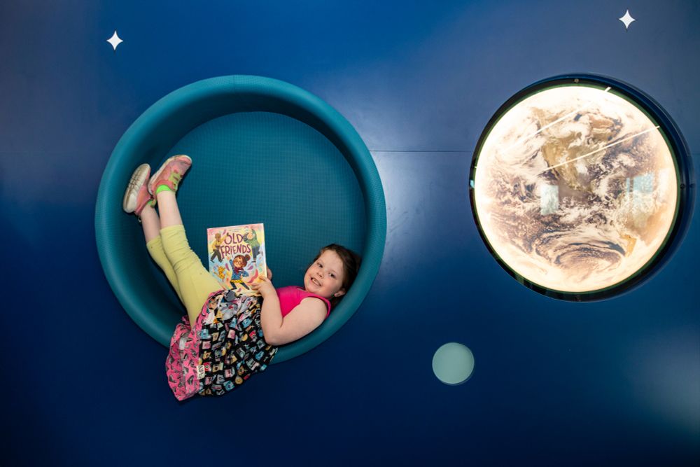 Smiling child in a round reading nook at the Glendale Branch of the Indianapolis Public Library.