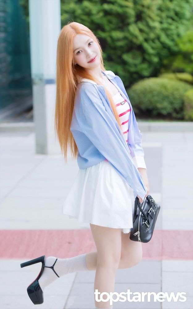 The singer Joy from Red Velvet posing outside with her recently dyed strawberry blonde hair