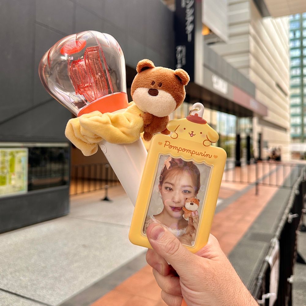 Outside the venue for Red Velvet Irene & Seulgi Balance concert in Japan. The author’s hand is holding a Red Velvet lightstick and Seulgi photocard in a Pompompurin photocard holder.