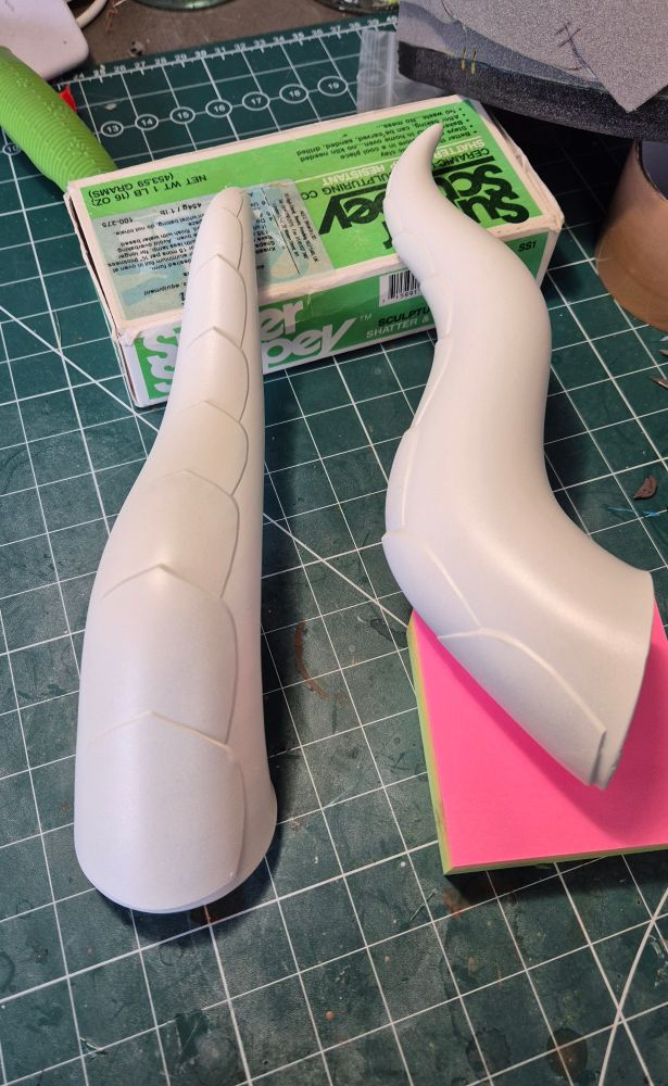 A photo of a pair of 3d printed horns that have been sprayed white as a base coat. There are no visible break lines on either of them.