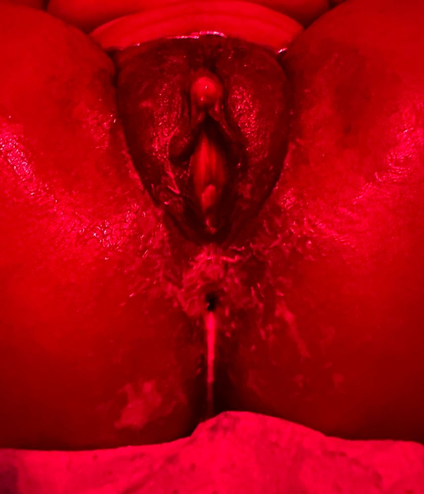 A messy hole drips lube and cream in red lighting. 