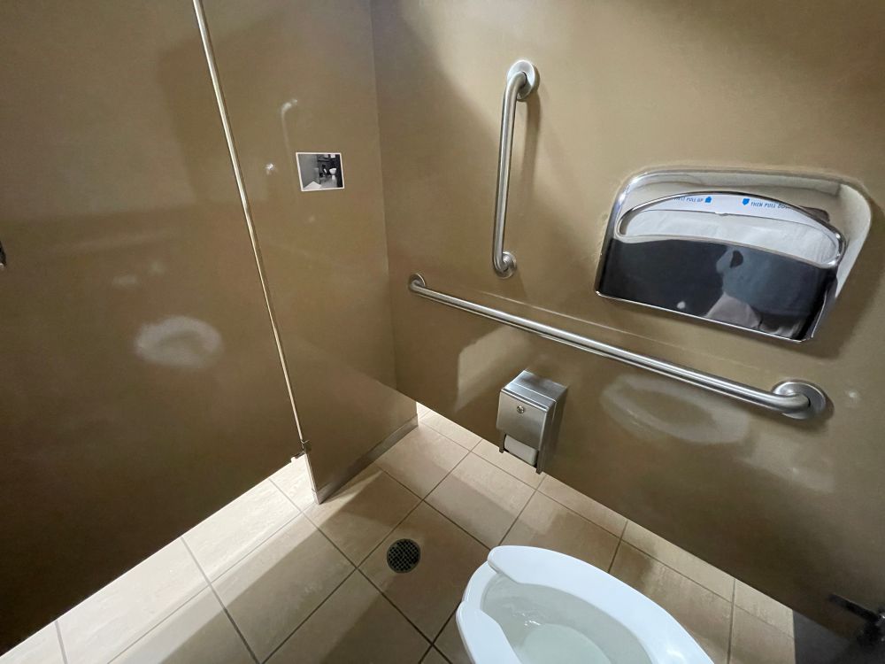 A photo hung on the wall of a bathroom stall. The photo is of the same bathroom stall. 