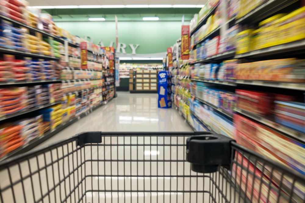 A shopping cart moves down an isle in a grocery store. 