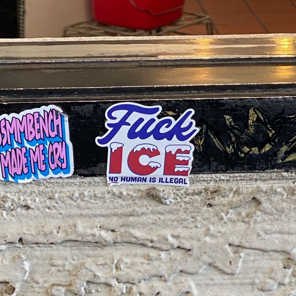a sticked posted to the bottom of a drive thru window. it reads, Fuck ICE, No Human Is Illegal