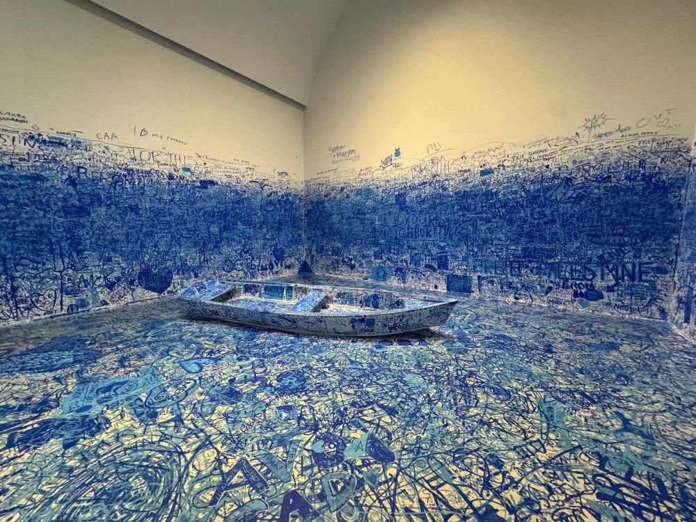 Yoko Ono, “Add Colour (Refugee Boat),” concept 1960– about in a large room full of blue scribbles, words and pictures from visitors 