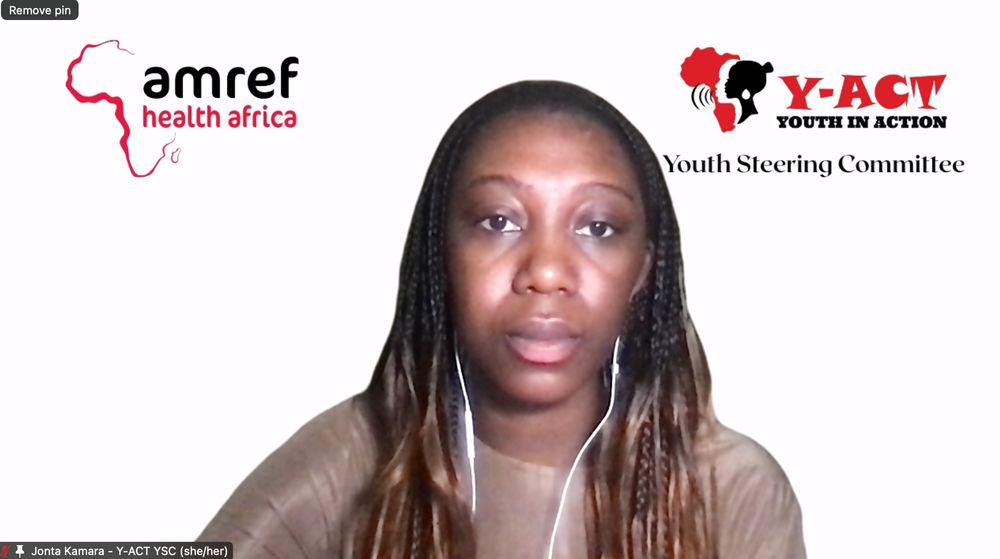 Screenshot of Jonta wearing a brown top staring at the camera. Behind her is a backdrop with the Amref Health Africa logo on the left and on the right is the Y-ACT logo with "Youth Steering Committee" written in black below it.