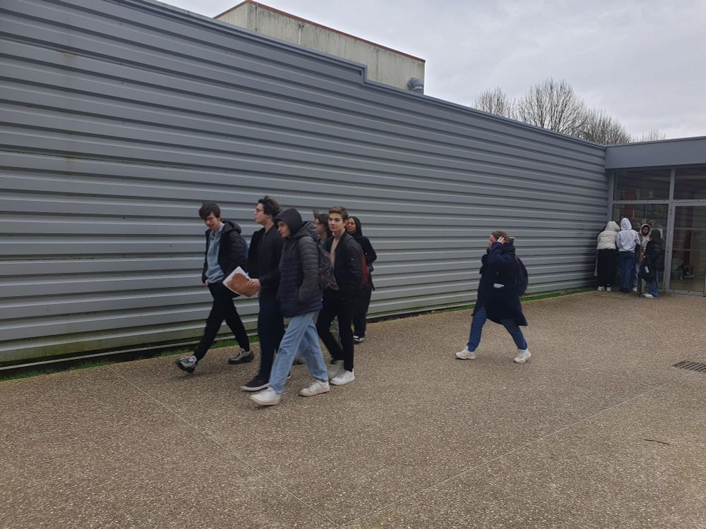 Les lycéens déambulent en groupe sur le campus de l'université à la recherche d'indices pour retrouver l'etudiant perdu.