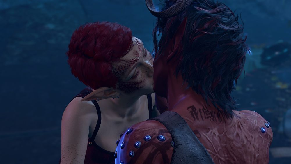 A screenshot from Baldur's Gate 3 showing a feminine-looking gnome with red scales on their face, short red hair, and freckles wearing a sleeveless shirt. They're leaning in and kissing Karlach, a red-skinned tiefling woman covered in scars.