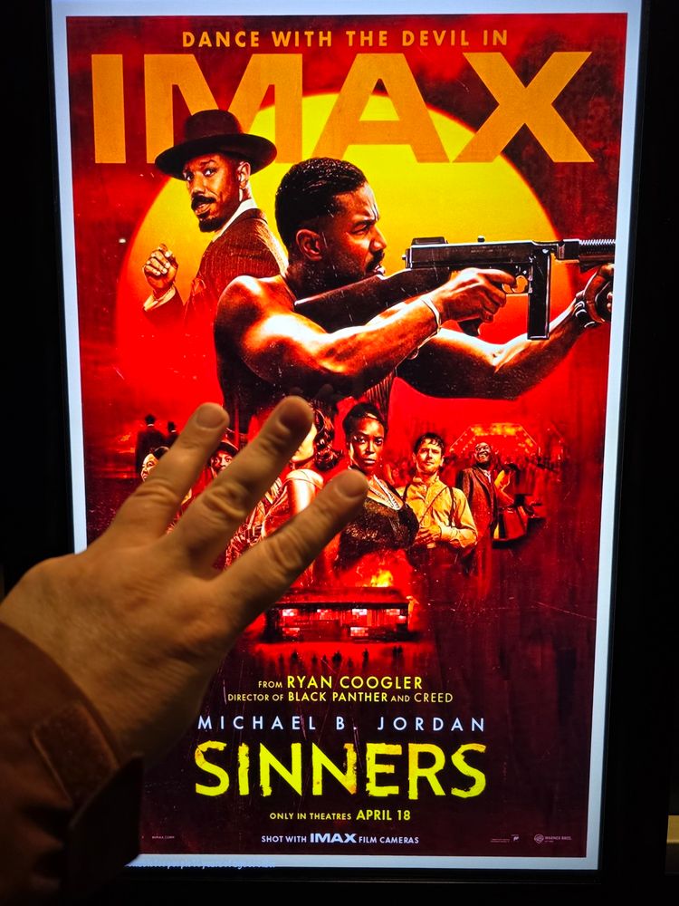 Image of three fingers being held up against the Sinners IMAX movie poster