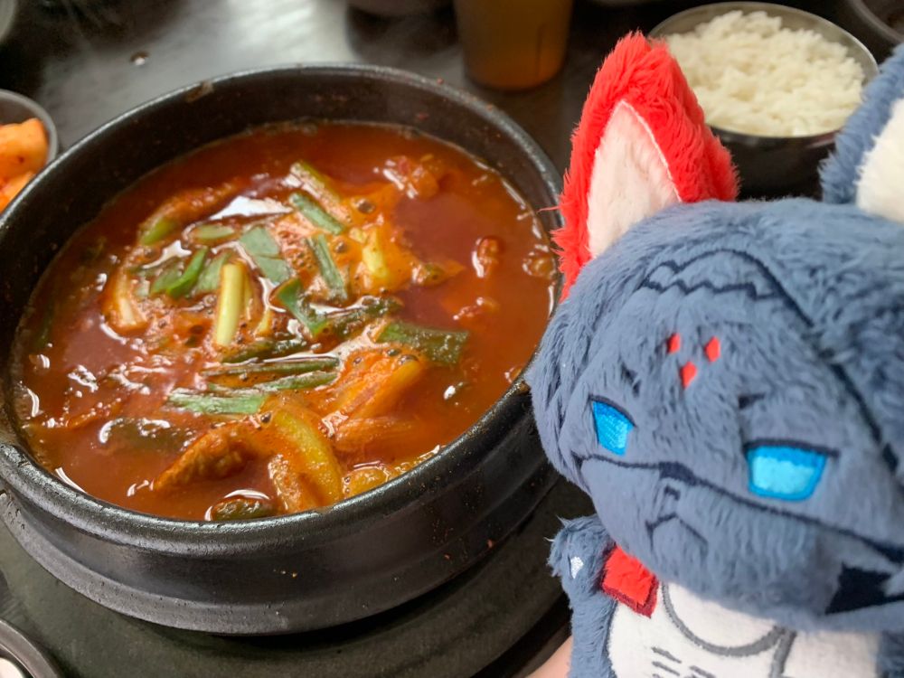 A Kolibri plush posed next to some daktoritang (Korean spicy chicken stew).