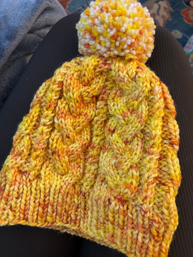 Bright yellow knitted hat with pompom. 