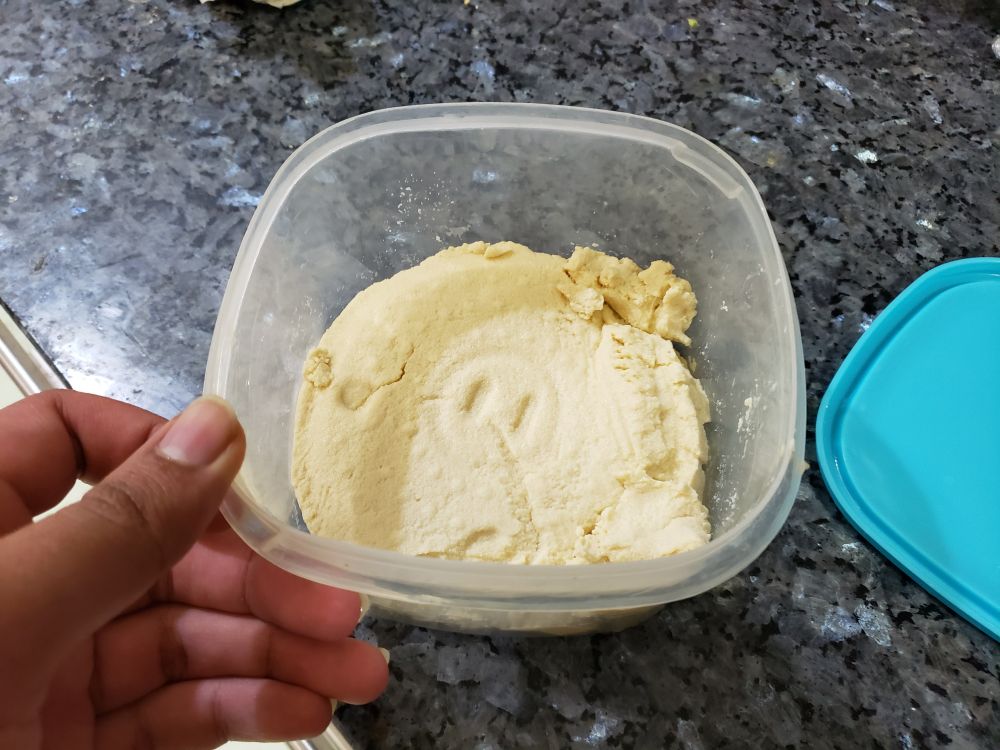 plastic container with homemade tofu. some pieces have crumpled and broken from the rest.