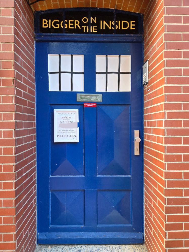 Eine Tür eingelassen in eine Backsteinfassade, die gestaltet ist wie die zur T.A.R.D.I.S. von Dr Who.