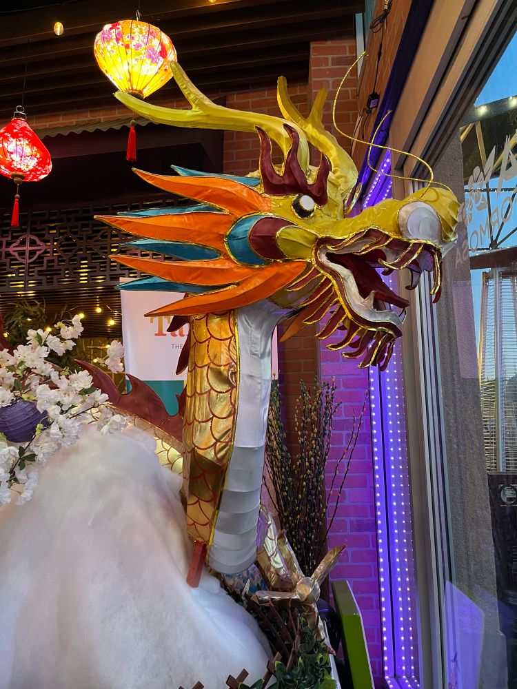 The head and neck of a gold Chinese dragon with fiery beard and whiskers, made from paper stretched over a frame 