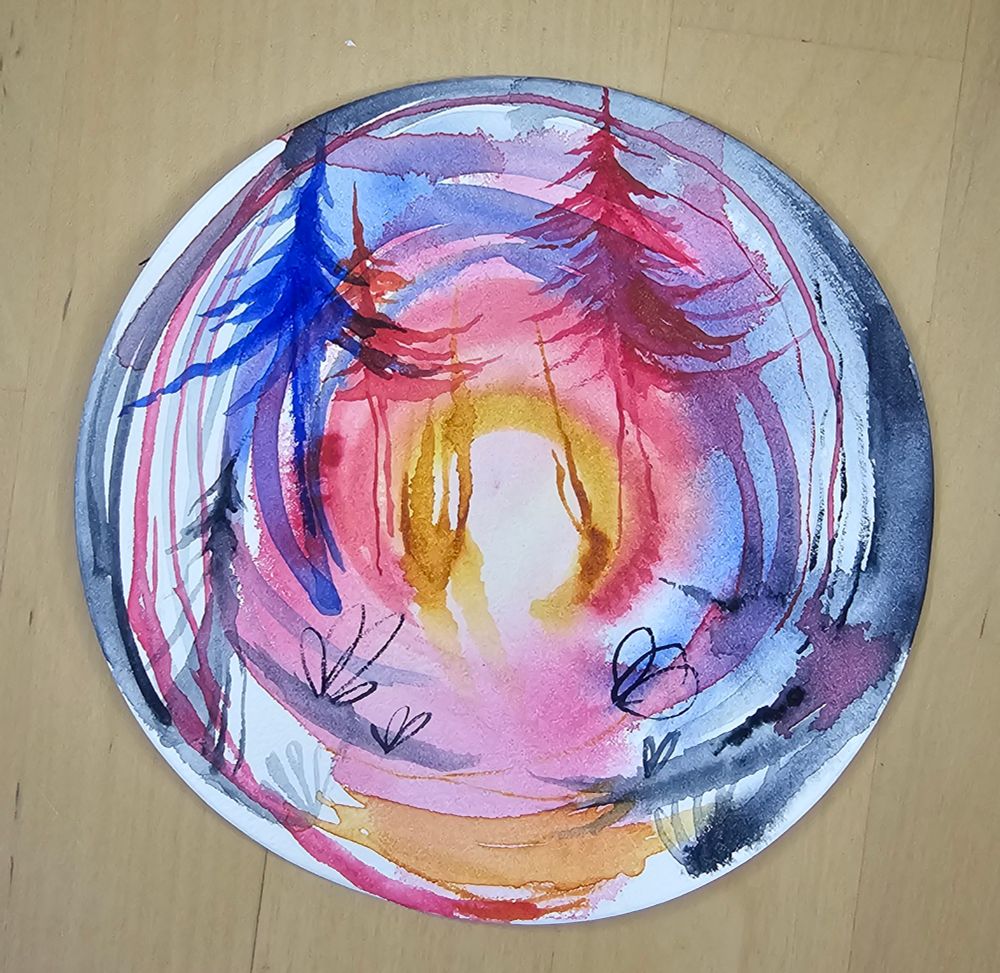 An abstract watercolor painting done on circle-shaped paper, with some recognizable forms of trees. The lighter pigments blend softly in the background, while bolder, clear forms come forward. The shapes and lines echo the circle shape, with colors in the center beginning white and spread from gold to red to blue to indigo.