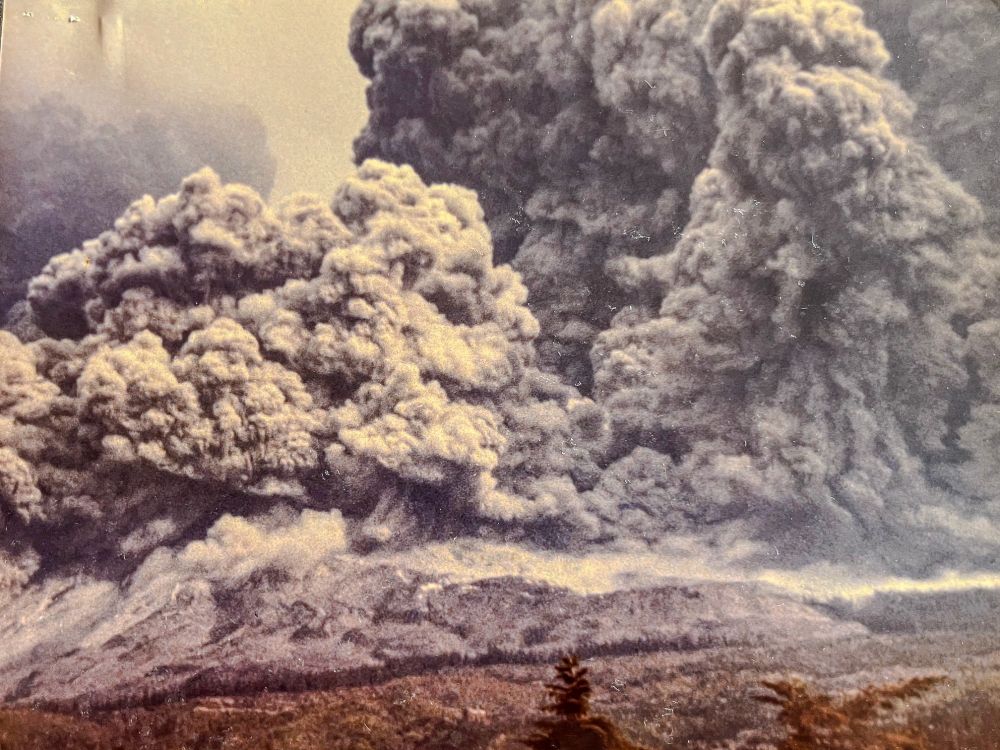 A thick, dark pyroclastic surge descends from the mountain’s crater toward the timberline, part of the lateral blast cloud sweeping outward. Multiple lobes of ash-filled turbulence spread outward, erasing the view.

Photo by Kevin Millican.
