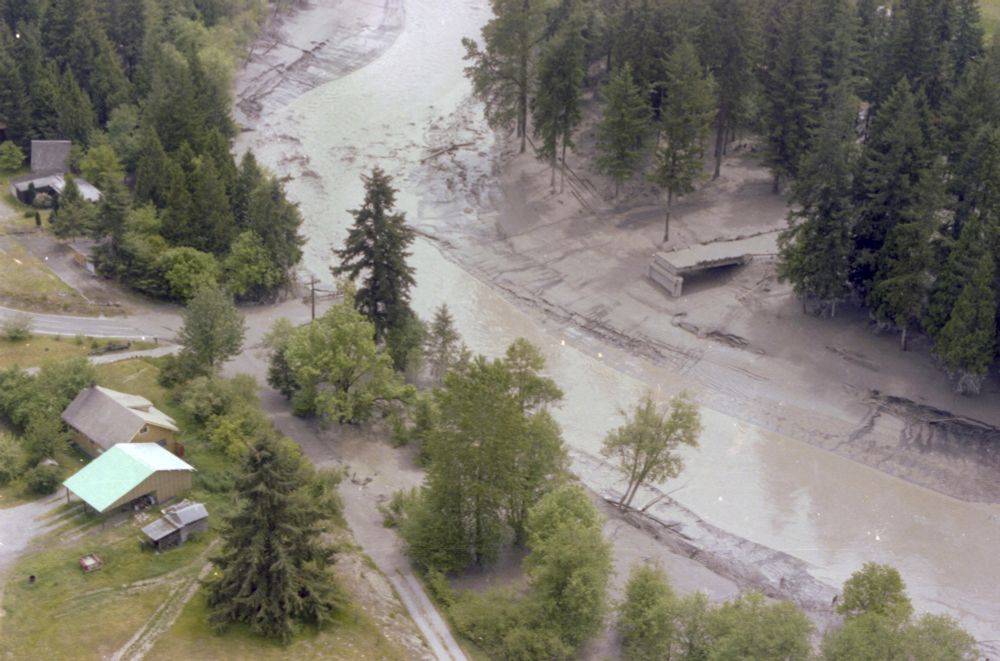Aerial view of the Tower Road Bridge over the Toutle River on May 19, 1980, one day after the Mount St. Helens eruption. The bridge’s main span has been washed away by mudflows, leaving only the western approach intact. Nearby homes sit beside a river thick with sediment and volcanic debris, the surrounding landscape blanketed in gray ash and silt.
Photographed by GB, Washington State Department of Transportation.