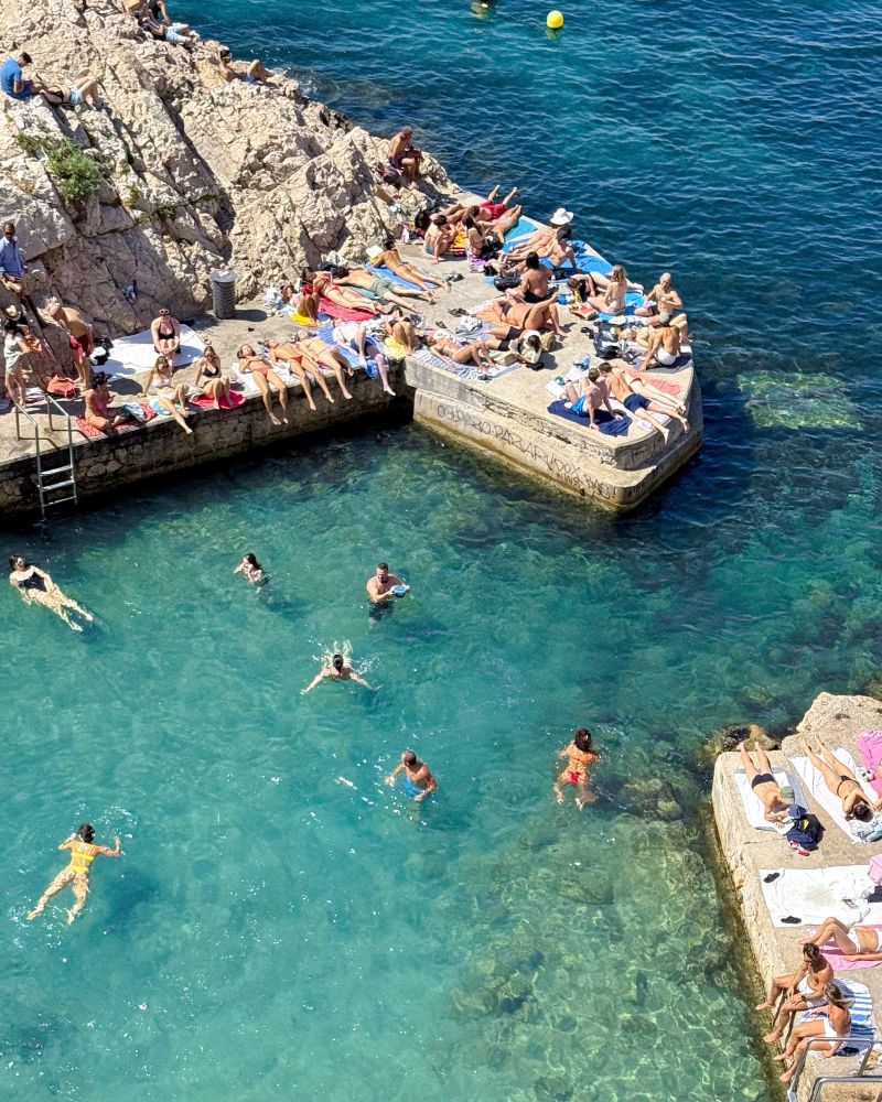 people swimming in the sea and sat on the rocks