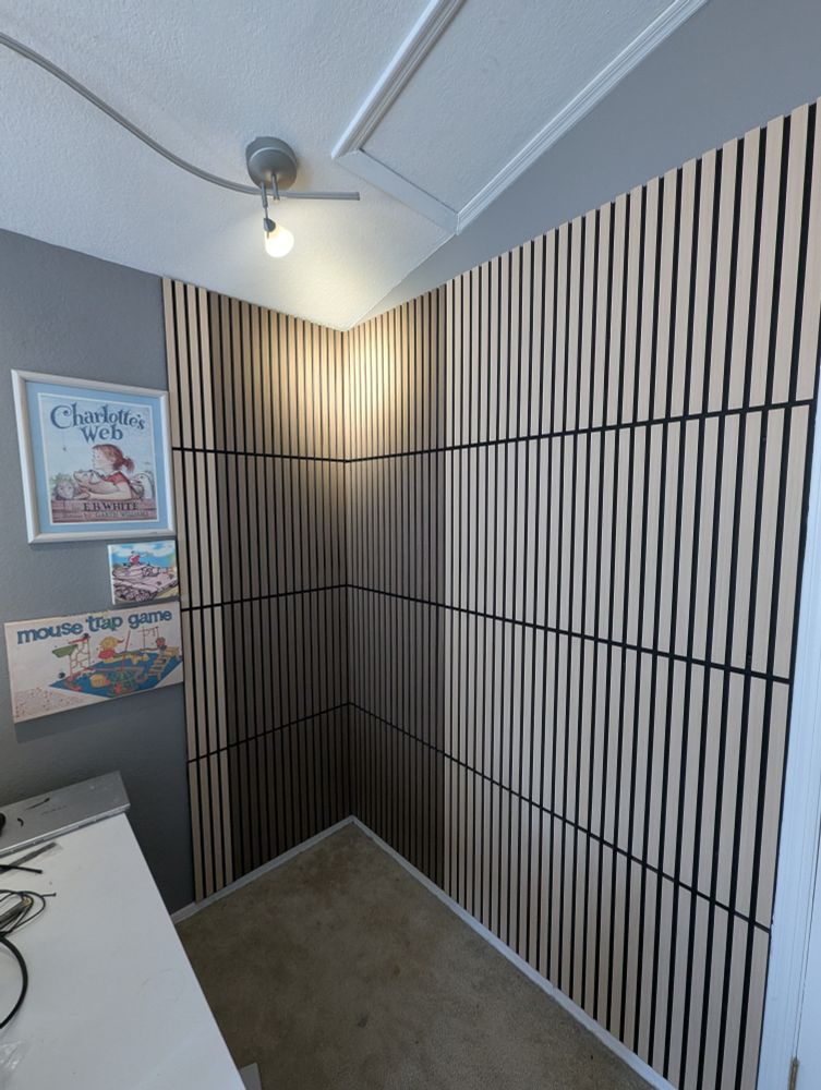 The corner of trobs office for music production. Newly installed dark walnut and light oak panels are on the wall. 