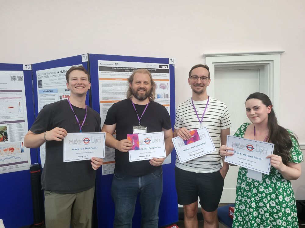 Four very happy people standing in front of poster boards holding prize-winning certificates.